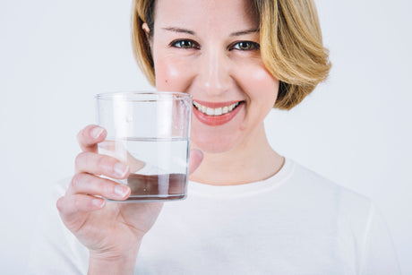 une femme joyeuse montrant un verre d'eau filtré